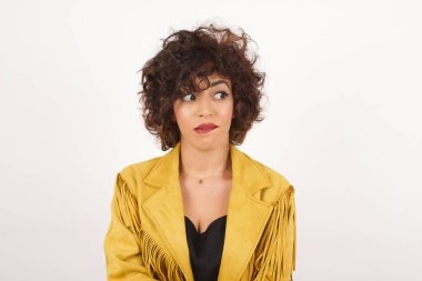 Düşünceli, genç bir kadın, bakışlarını kaçırıyor, dudaklarını ısırıyor, gri duvara karşı hoş bir poz düşünüyor..