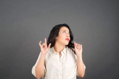 Gayri resmi giyinmiş güzel esmer kadın. Gri arkaplanda duruyor. 