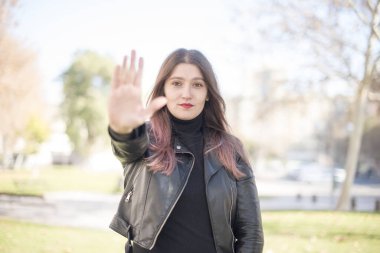 Parkta dur hareketi yapan genç ve güzel bir kadın.