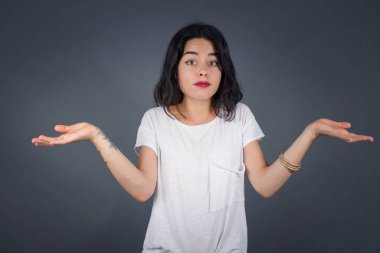 Güzel bir kadın ifadeden şüphe eder, şaşırır ve şaşırır, belirsiz bir gelecek omuzlarını silker, gri duvara karşı durur..