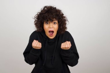 Güçlü, kararlı, sıradan giysiler içinde kollarını kaldırıp yumruklarını sıkan genç bir kadının belindeki portreyi kaldır. Zafer, başarı ve başarı kavramı.