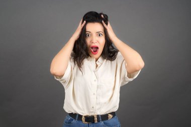 Güzel esmer kadın şaşırdı. Gri arkaplanda duruyor. 