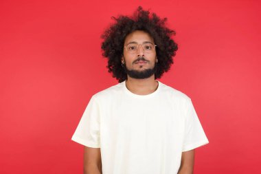 Kızıl duvara karşı poz veren afro saçlı genç adam. 