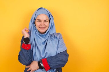 Orta yaşlı, neşeli, tesettürlü Müslüman bir kadının yüzü duvara yakın bir şekilde duruşu.. 