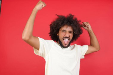 Kızıl duvarda kutlama yapan afro saçlı genç adam.   