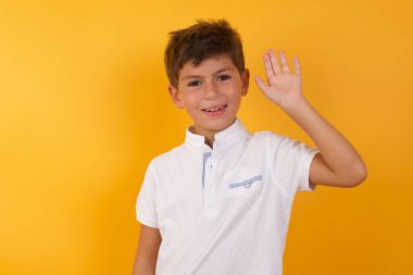 Sarı duvara yaslanmış sevimli çocuk.  