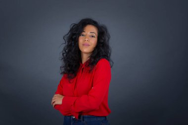 Güzel, kendine güvenen, neşeli, kıvırcık saçlı, kırmızı gömlekli, kolları çapraz saçlı, şık giyinmiş, iş arkadaşıyla tanıştığına sevinen esmer bir kadının belden yukarısını çek..