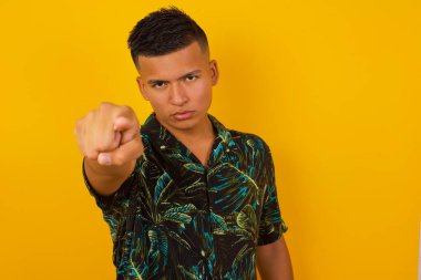 İçeriden çekilen günlük kıyafetler içindeki neşeli, genç İspanyol adam size mutlulukla bakıyor, rekabeti seçiyor, olumlu bir ifadeye sahip. Yakışıklı zeki öğrenci, gri duvarda izole edilmiş bir şekilde seçim yapar.