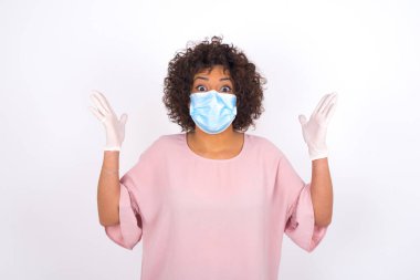 Yüz maskesi takan ve günlük kıyafet giyen kadın beyaz stüdyo arka planında izole edilmiş.