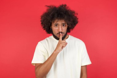 Kızıl duvara karşı sessiz hareketli afro saçlı genç adam. 