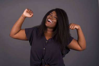 Evet, ben kazandım. Çekici, keyifli ve heyecanlı Afro-Amerikan kadının portresi zafer ve zaferle yumruğunu kaldırıyor gülümseyerek mutluluktan sırıtarak başarı elde ediyor..