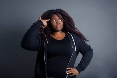 Mutsuz Afro-Amerikan kadın günlük giysiler içinde dudaklarını kıvırıyor ve intihar jesti yapıyor, her şeyden bıkmış, sinagogda elle çekim yapıyor, stüdyo arka planına karşı izole edilmiş. Kapalı mekanda kadın hareketleri, kendini öldürmeye çalışır.