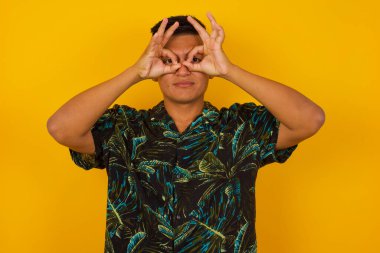 Neşeli, heyecanlı İspanyol erkek OK hareketlerini iki eliyle gösteriyor, gözlük takıyormuş gibi yapıyor, hayret verici bir şey gördüğüne şaşırıyor. Duygular, vücut dili ve jestler 