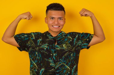 İspanyol adamın belden yukarı vuruşu kollarını kaldırarak zaferden emin olduğunu, güçlü ve bağımsız göründüğünü, kameraya olumlu gülümsediğini, gri arka planda durduğunu gösterir. Spor konsepti.