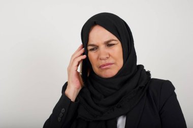 Stüdyoda akıllı telefonlu, tesettürdeki orta yaşlı Müslüman kadın izole edilmiş bir geçmişe sahip. 