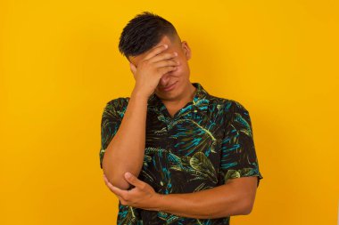 Havalı saç kesimi olan, sıradan kıyafetler giyen, gülümserken fotojenik hareketler yapan, arka planda dikilen yakışıklı İspanyol adamın kapalı bir portresi..