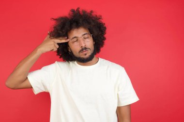 Kızıl duvara karşı silahlı afro saçlı genç adam.   