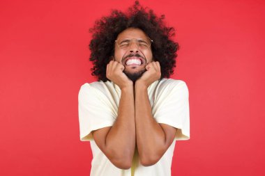 Kızıl duvara bağıran afro saçlı genç adam.   