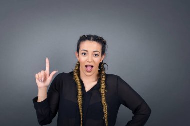 Hoş görünümlü mavi gözlü genç kadın modelinin yakın portresi zekice bir ifadeye sahiptir, bir parmağını kaldırır, önemli bir şeyi unutmaması gerektiğini hatırlar..