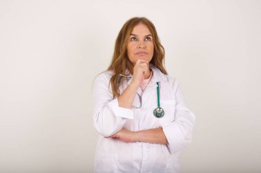 Düşünceli gülümseyen bir doktorun portresi elini çenesinin altında tutar, yan bakar, ilginç bir şey düşünür ya da merak eder.