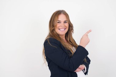 Şuraya bakın! Güzel orta yaşlı beyaz kadın, gri arka planda dururken seni işaret ediyor ve gülümsüyor..