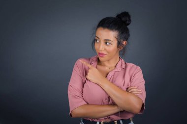 Kamerada poz veren güzel esmer bir kadın. Alengirli bir bakışla ve el kol hareketleriyle. Bayan tasarımcı işaret parmağıyla güzel bir ürün sunuyor..