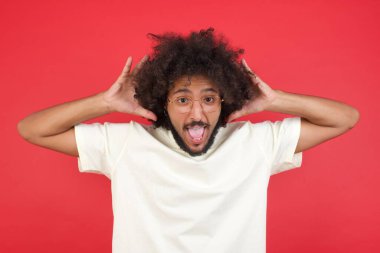 Kızıl duvarda afro saçlı kafası karışık genç adam. 