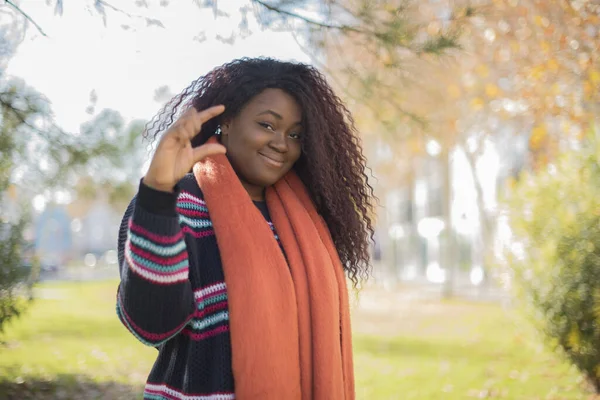 秋の公園で少しを示すカラフルなセーターを身に着けている長い髪の美しいアフリカ系アメリカ人女性 — ストック写真