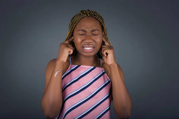 不幸なことに 若いアフリカ系アメリカ人女性が顔を洗い 指で耳を差し込み 大きな騒音でイライラしたことを強調した — ストック写真