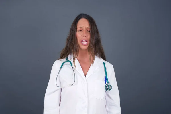 Negative human expressions and attitude. Angry dissatisfied doctor female has disgusting expression as sees something not appealing, frowns face, isolated over white  background. Distaste and dislike.