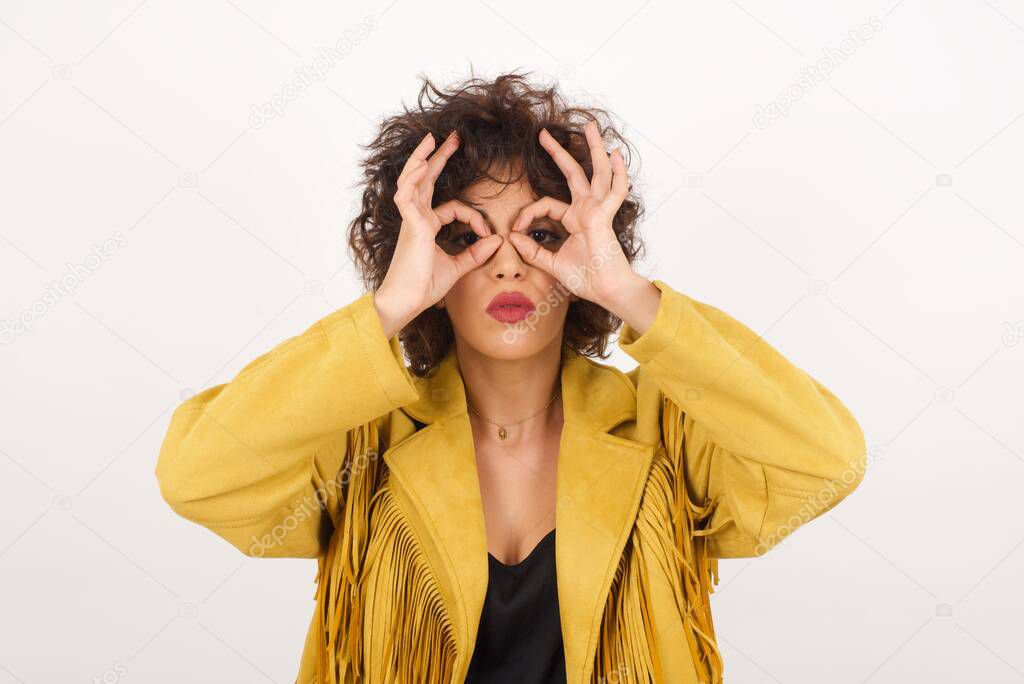 Beautiful  woman in suede jacket showing glasses with fingers  studio shot