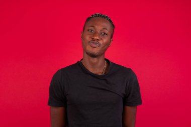 Çekici Afro-Amerikan erkeği dudaklarını yuvarlar, günlük kıyafetler giyer, doğrudan kameraya bakar, memnuniyetini ifade eder, arka planda soyutlanır. İnsanlar, vücut dili kavramı 