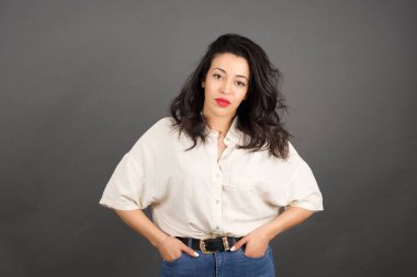 Gri arka planda gelişigüzel giyinmiş güzel esmer kadın..  