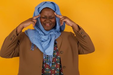 Genç ve güzel bir Afrikalı Amerikalı Müslüman kadın ciddi bir bakışla bir fikre odaklanmış, her iki işaret parmağı da alnı kapalı bir şekilde düşünüyor..