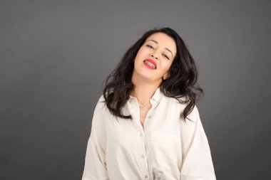 Gayri resmi giyinmiş güzel esmer kadın. Gri arkaplanda duruyor. 