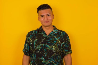 Yakışıklı, esmer, kıvırcık saçlı, sevimli gülümsemeli, beyaz, boş fotokopi duvarına poz veren yakışıklı İspanyol modelin yakın çekimini yapın.