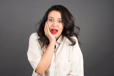 Gündelik giyinmiş güzel esmer kadının gri arka planla kafası karışıyor..  