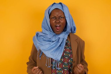 Güçlü, kararlı, genç, Afrikalı, Müslüman bir kadının portresi. Sıradan giysiler içinde, kollarını kaldırarak, yumruklarını sıkarak, sevinçle golü haykırarak kazandı. Zafer, başarı ve başarı kavramı.