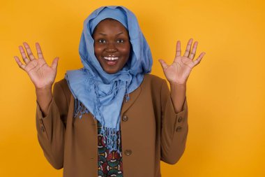 Başarı, başarı konsepti. Neşeli Afrikalı Amerikalı Müslüman kadın ellerini kaldırıyor, mutluluk dolu gözleriyle büyük başarılarını kutluyor. Resmi olarak giyinmiş çekici beyaz kadın.. 