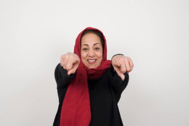 Kamerayı iki parmakla işaret eden olgun Müslüman kadının yakın plan portresi: 