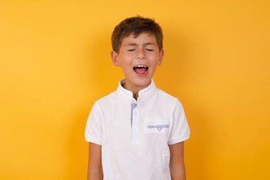 Sarı duvara karşı bağıran sevimli çocuk.  