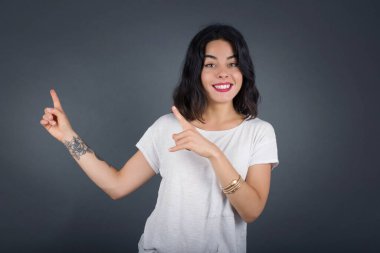 Reklam konsepti. Gri arka planda kot gömlekli, parlak gülüşü olan pozitif, güzel, beyaz kadın işaret parmağıyla işaret ediyor ve boş fotokopi odasına bakıyor..