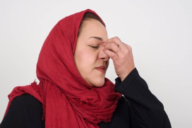 Çok üzgün bir kadın burnuna dokunuyor, ağlamak istiyor, stresli bir ilişkisi var, yorgun, işle ilgili sorunları var. Stüdyoda poz veren başörtüsü takan orta yaşlı bir Arap kadın.
