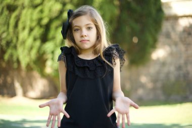 Kafası karışmış, siyah elbiseli, omuzlarını silkip 