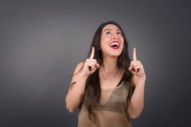 Gri arka planda ayakta duran güzel bir kadın. 