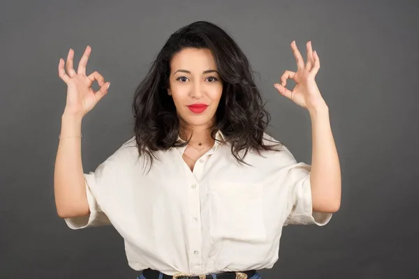 Hermosa Mujer Morena Vestida Casualmente Mostrando Contra Fondo Gris — Foto de Stock