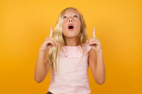 Schattig Klein Meisje Roze Jurk Tegen Gele Studio Achtergrond Pointingup — Stockfoto