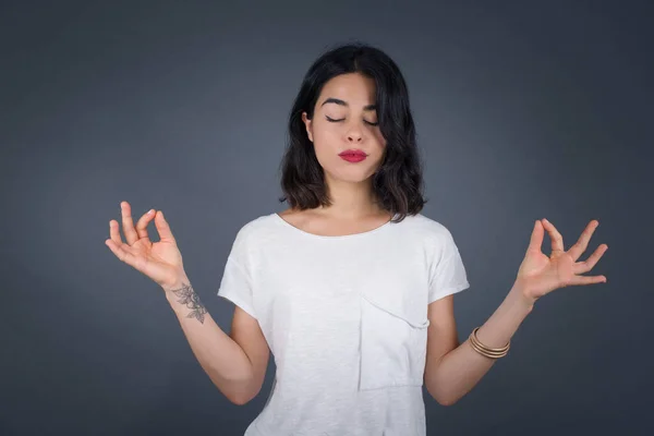 Meditation, religion and spiritual practices. Beautiful young blond haired female doing yoga in the morning outdoors after waking up, keeping eyes closed, holding fingers in mudra gesture.