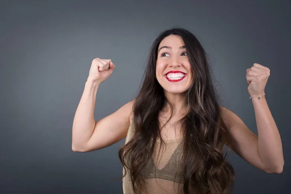 Beautiful  woman with fists . Standing against gray background.