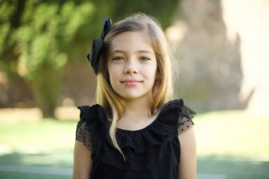 Güzel bir genç kızın parkta poz verirken sevimli bir gülümsemeyle kameraya baktığı stüdyoyu kapat. 